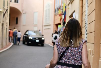 Rear view of woman standing on street in city