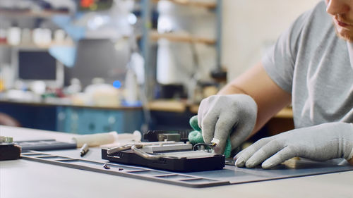 Midsection of man repairing computer equipment on table