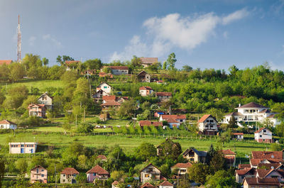 Houses on field by buildings against sky