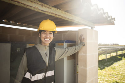 Portrait of smiling female engineer leaning on pillar of control room at power station