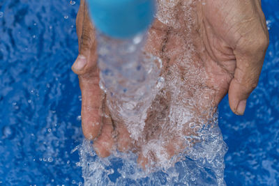 Water splashing on cropped hands at swimming pool