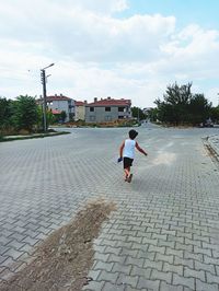 Rear view of woman on footpath against sky