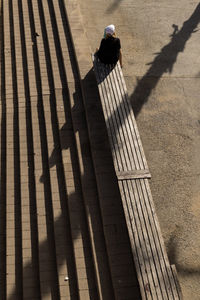 High angle view of woman sitting on bench during sunny day