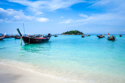 Fishing boats moored on sea against sky