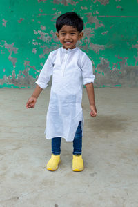 Portrait of smiling boy standing against wall