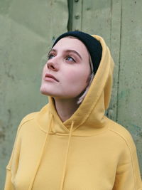 Close-up of beautiful woman standing against yellow wall