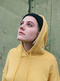 Close-up of beautiful woman looking up against wall