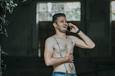 Young man holding camera while standing outdoors