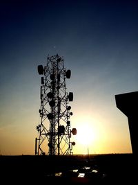 Low angle view of silhouette communications tower against sky during sunset