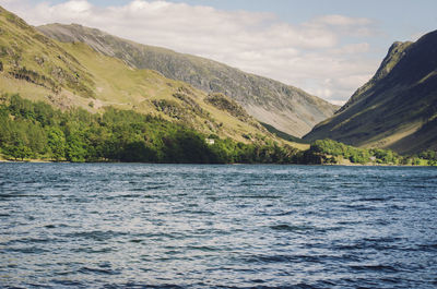 Scenic view of sea by mountains against sky