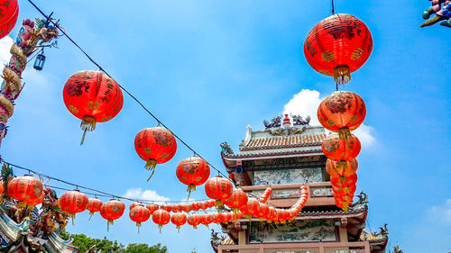 Low angle view of lanterns hanging by building against sky