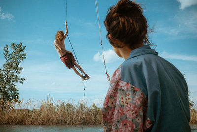 Side view of woman looking at fish in lake