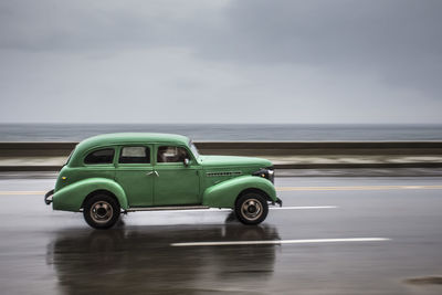 Vintage car on sea against sky