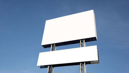 Low angle view of arrow sign against clear blue sky