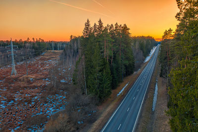 Road amidst trees against sky during sunset