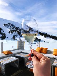 Woman holding champagne flute against snowcapped mountain