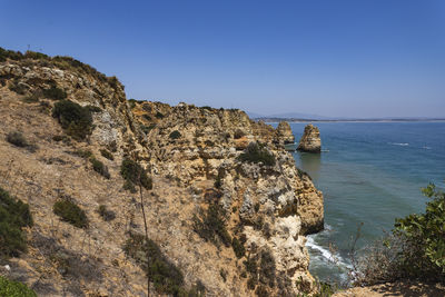 Rock formations by sea against clear sky