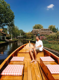 Man sitting on boat against sky