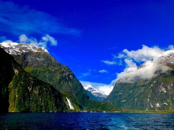 Scenic view of sea and mountains against blue sky