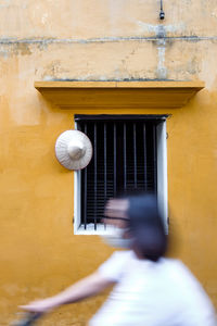 Side view of blurred woman riding past a wall in hoi an old town, vietnam