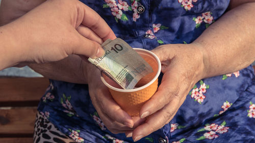 Cropped hand of person giving beggar paper currency