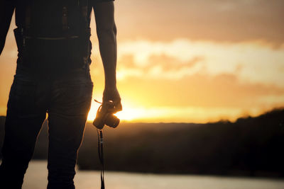 Silhouette man photographing against sky during sunset