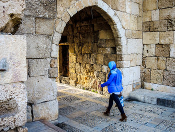 Rear view of woman walking on stone wall