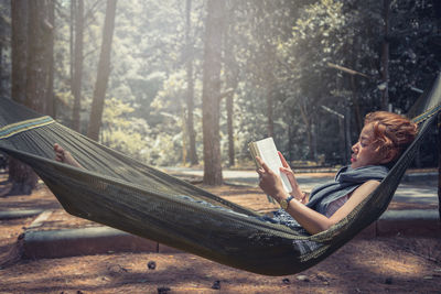 Woman sitting on hammock in forest