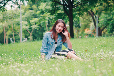 Full length of smiling young woman sitting on land