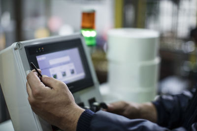 Close-up of worker operating machine in factory