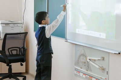 Side view of boy standing against wall