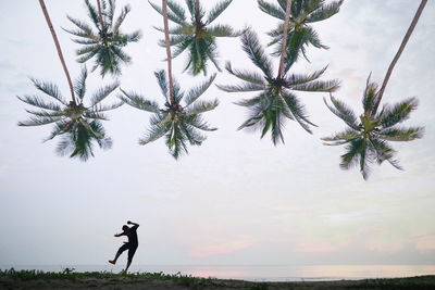 Silhouette man dancing at beach against sky