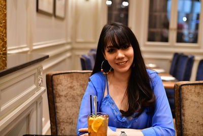 Portrait of a smiling young woman sitting at restaurant