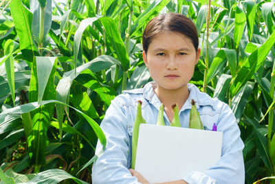 Young woman holding corn on field