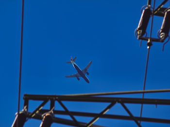 Low angle view of airplane flying against clear blue sky