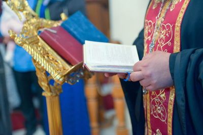 Midsection of priest holding bible