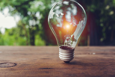 Close-up of illuminated light bulb on table