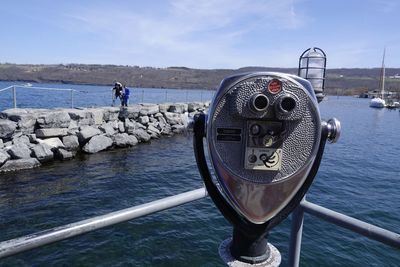 Coin-operated binocular by sea against sky