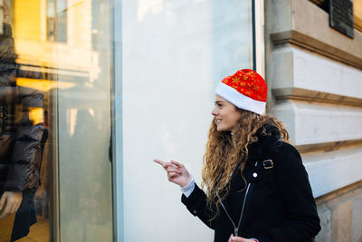 Surprised woman pointing window display of store in city