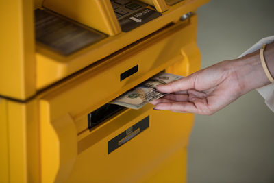 Cropped hand of woman using atm