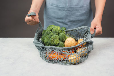 Mesh bag with vegetables, shopping grocery, healthy food ingredients, potato, broccoli and carrots
