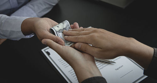 Cropped hands of man giving bribe