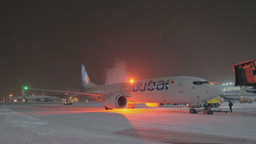 Airplane on airport runway against sky at night