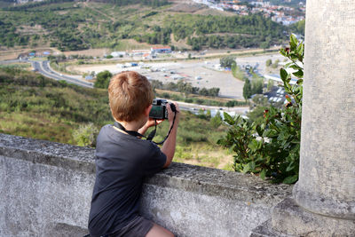A boy with a camera photographs the city from the top of the observation deck.