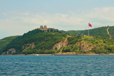 Turkish flag on mountain by lake against sky