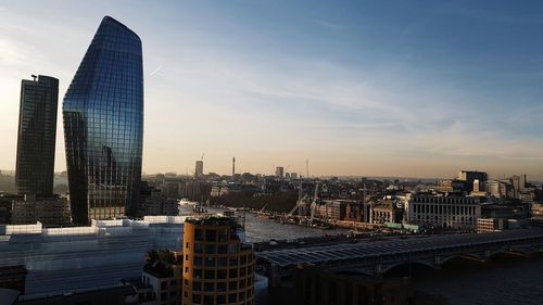 Modern buildings in city against sky during sunset