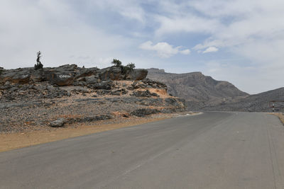 Road by desert against sky