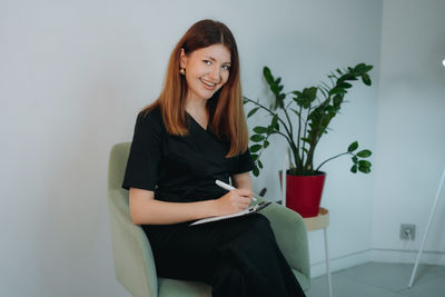 Portrait of young woman using mobile phone while sitting at home