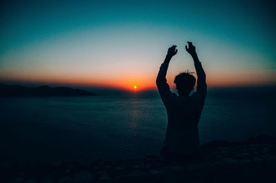 Silhouette woman standing by heart shape against sky during sunset