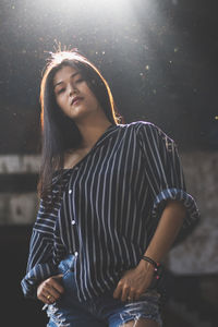 Young woman standing against illuminated wall at night